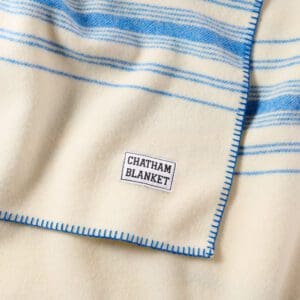 Close-up of a cozy cream and blue striped blanket with a label.
