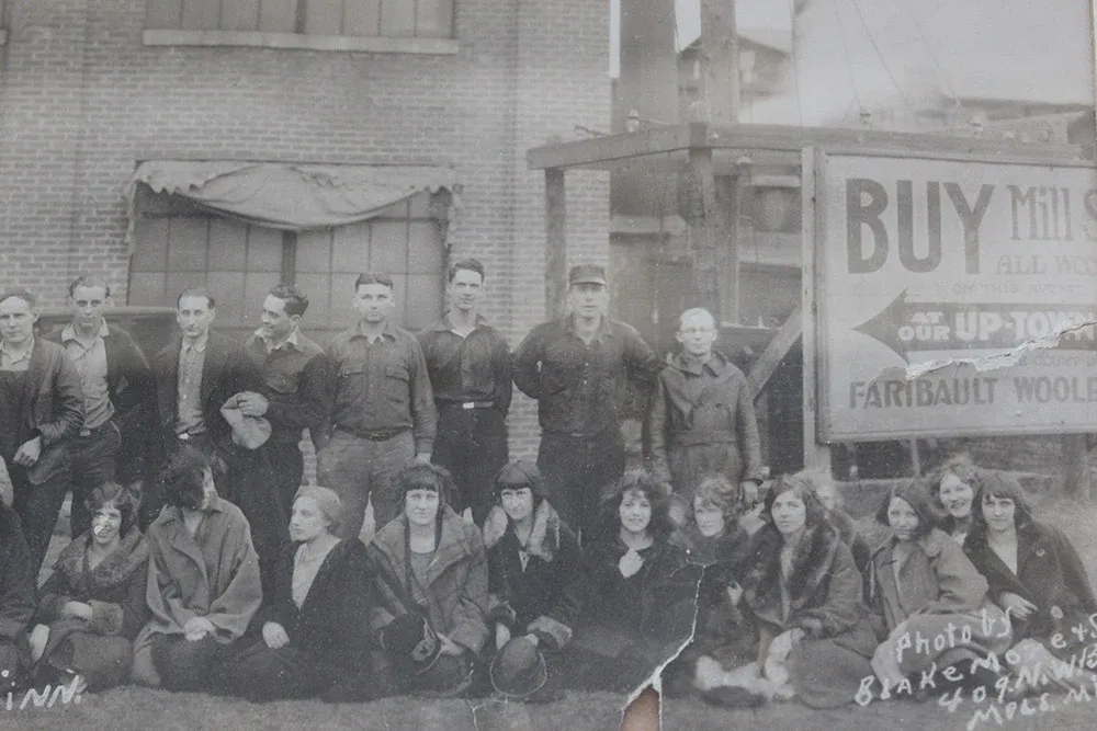 Black and white photo of a group posing outside a building.