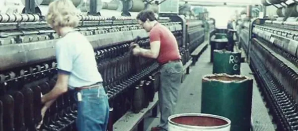 Woman working on a textile machine in a factory.
