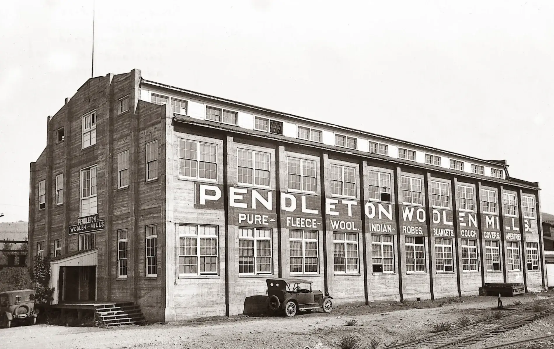 Historic Pendleton Woolen Mills factory with vintage cars outside.