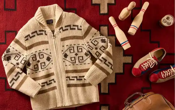 A cozy cream sweater with dark geometric patterns on a red surface.
