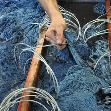 Hands working with blue fishing nets and ropes.