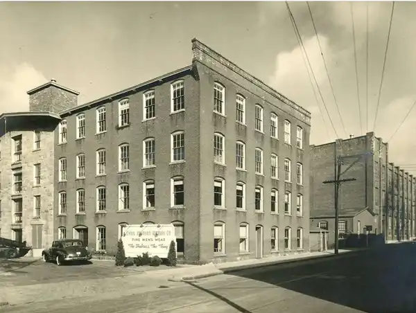Historic four-story brick building at a street corner with vintage cars.