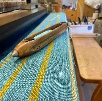 A wooden canoe model on a patterned fabric surface.