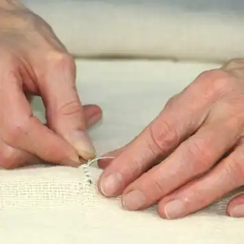 Hands reading braille on a textured surface.