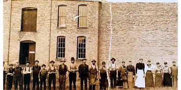 Vintage photograph of men standing in front of a brick building.
