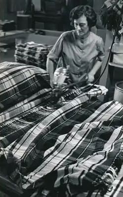 Hands making a peace sign over a plaid blanket.