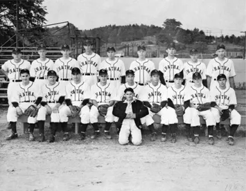 Black and white photo of a vintage baseball team posing with their coach.
