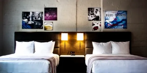 Modern hotel room with two beds and stylish wall art.